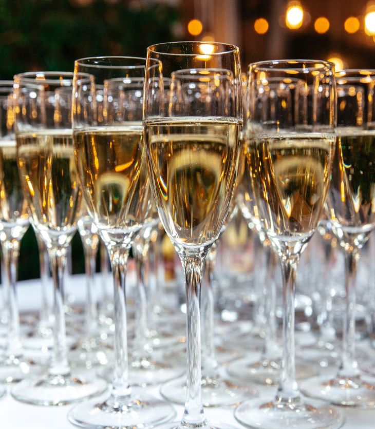 Rows of flutes filled with pale sparkling wine on a table at a celebration