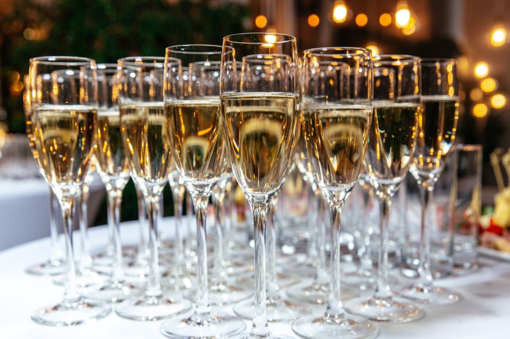 Rows of flutes filled with pale sparkling wine on a table at a celebration